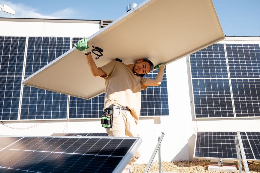 Technician carefully removing a solar panel during maintenance work on a rooftop