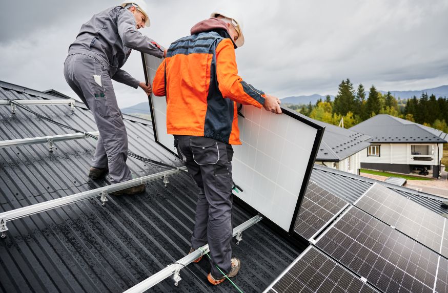 Technicians reinstalling solar panels on a metal roof by First Solar Installers, showcasing companies that remove and reinstall solar panels.