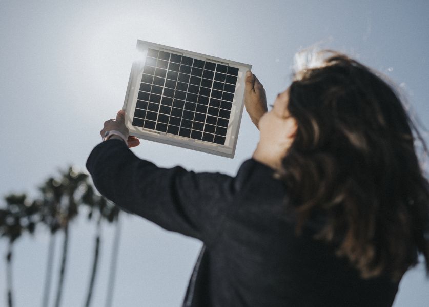 Person holding a small solar panel toward the sunlight – demonstrating solar panels without battery setup by First Solar Installers