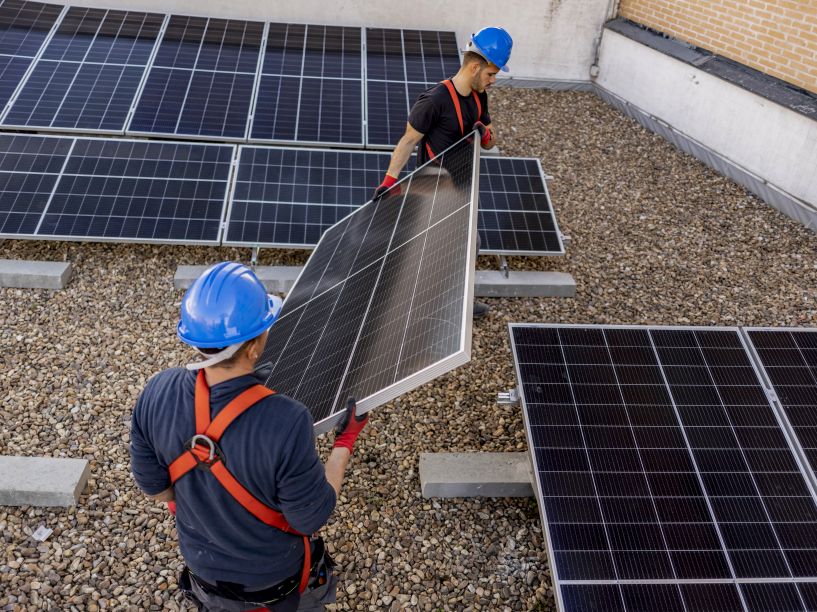 First Solar Installers team lifting a solar panel during rooftop removal, illustrating the professional process and real cost to remove solar panels safely.