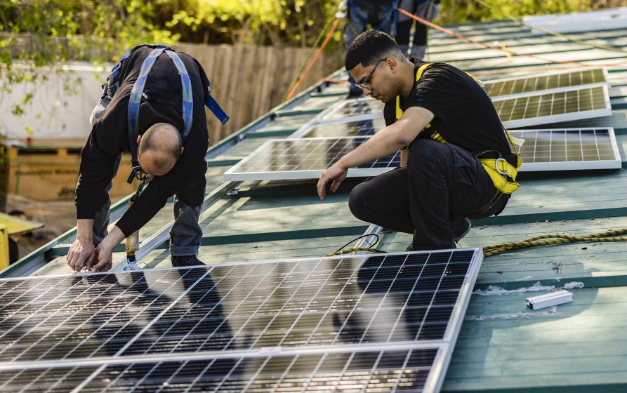 Technicians from First Solar Installers carefully removing rooftop solar panels during a system maintenance project, showing the real cost to remove solar panels